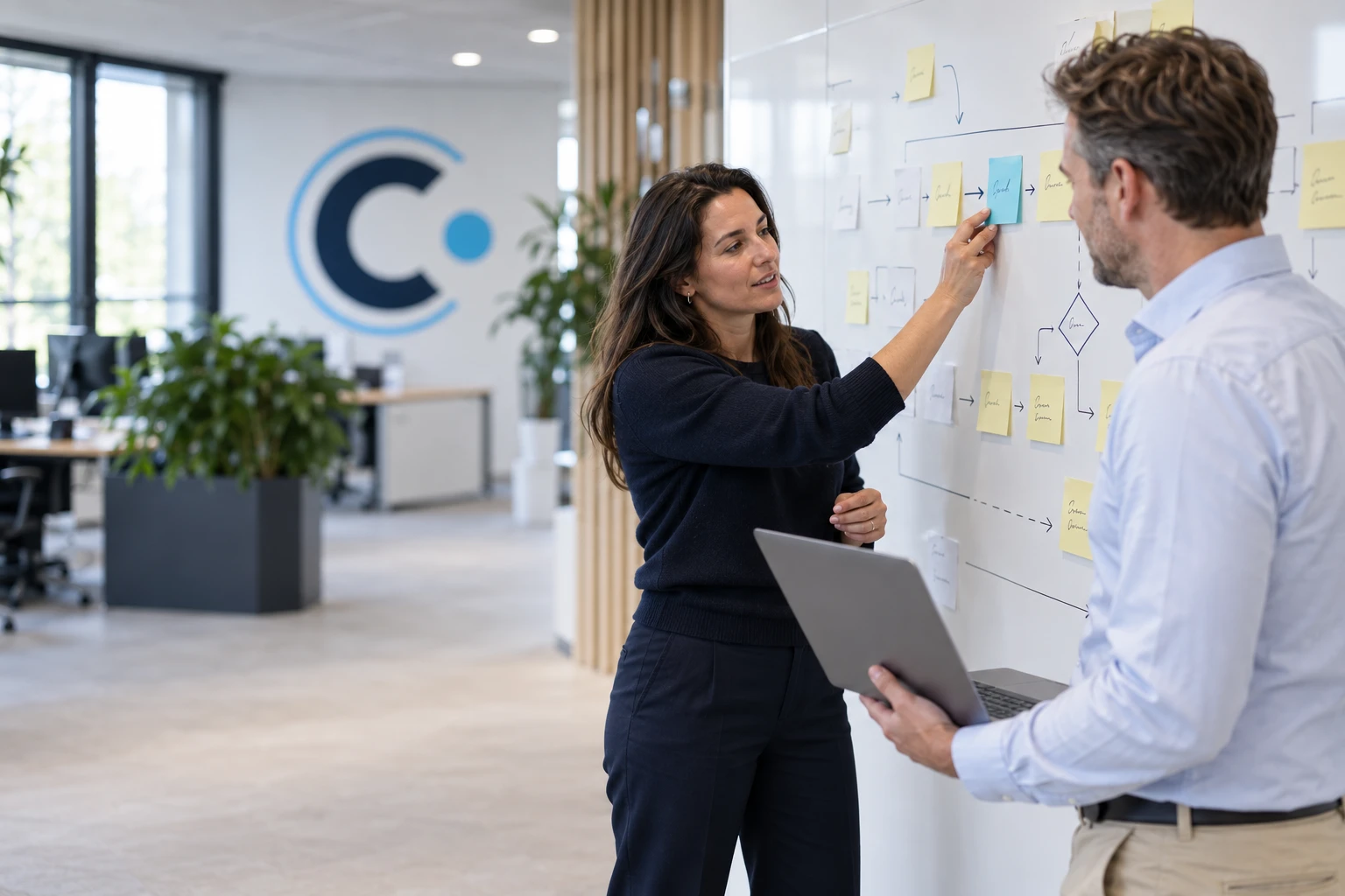 Connect IT-consultant plakt een tealkleurige notitie op een processchema tijdens een workshop met een klant